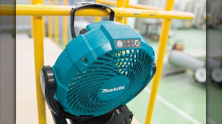 Makita fan mounted on a yellow railing.