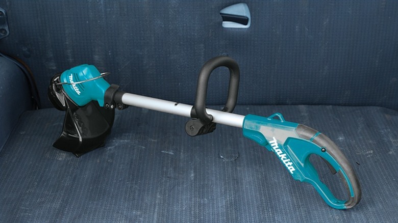 Makita string trimmer placed at the back of a pickup truck.