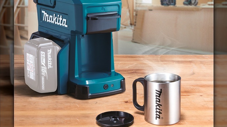 Makita coffee maker placed alongside a Makita mug on a wooden surface.
