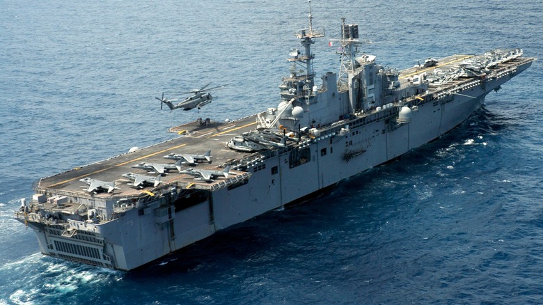 A CH-53E Super Stallion lifting pallets off USS Bataan