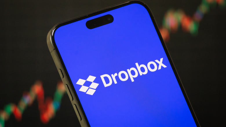 DropBox logo on a smartphone screen with a rising stock tracker in the background