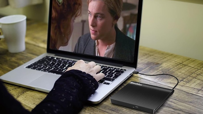 A person watching a movie on a laptop via the Rioddas external DVD drive