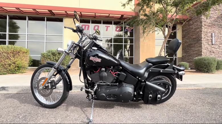 Harley-Davidson Night Train motorcycle in black with chrome V-twin engine, high-rise ape hanger handlebars, passenger backrest, and custom exhaust, displayed indoors at dealership