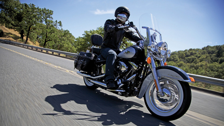 lassic Harley-Davidson Heritage Softail motorcycle with leather saddlebags, windshield, and spoked wheels in brown and chrome finish