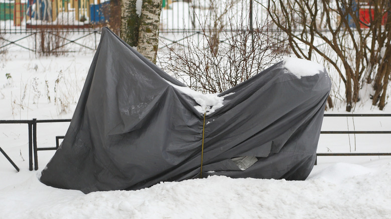 Motorcycle parked in the snow with a cover on