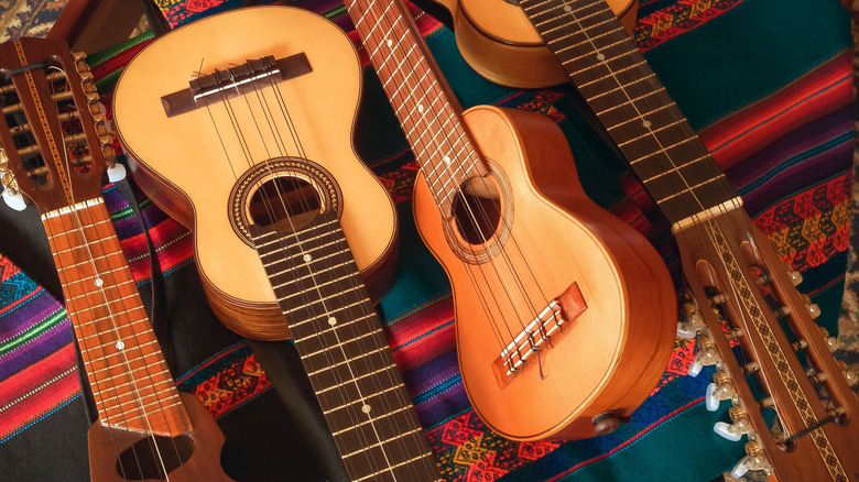 Four musical instruments in the shape of guitars but with varying sizes and number of strings.