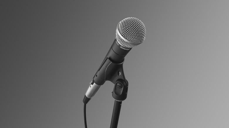 The Shure SM58 microphone on a stand on a gray background.