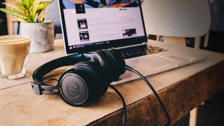 The Audio-Technica ATH-M60x headphones placed near a laptop and a cup of coffee on a wooden table