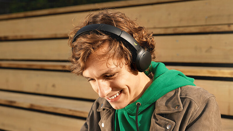 A person smiling and looking down while wearing the Edifier WH500 headphones