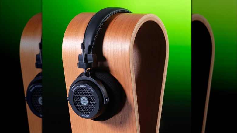 The Grado GW100x headphones placed on a wooden stand on a green-black background