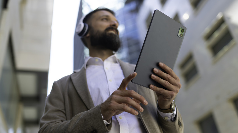 A person wearing on-ear headphones and holding a tablet