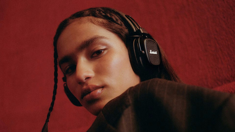 A person wearing a pair of Marshall Major V headphones on a red background
