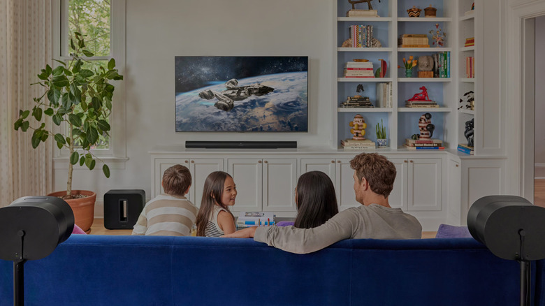 The Sonos Arc Ultra soundbar and the Sub 4 subwoofer placed in a living room as a family of four watch TV