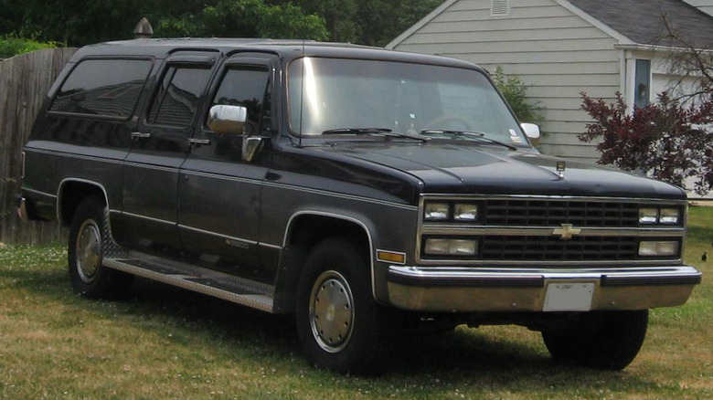 A black 1990 Chevy Suburbian parked in the grass