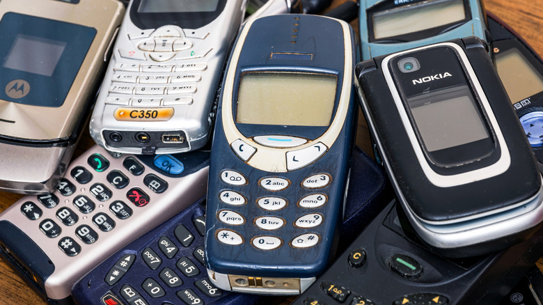 Old Nokia, Ericsson and Motorola cell phones piled on a table