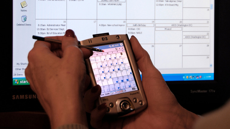Using a PDA to organize and synchronize her personal calendar with a desktop computer.