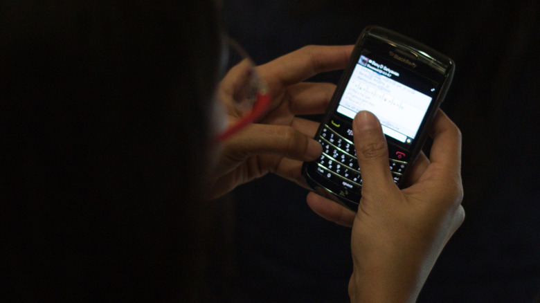 A women writing a message on a blackberry phone.