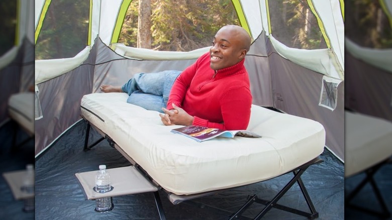 man laying on Coleman air mattress in tent