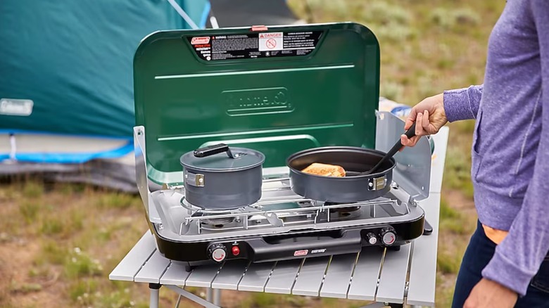 Camper cooking on a Coleman 3-burner stove
