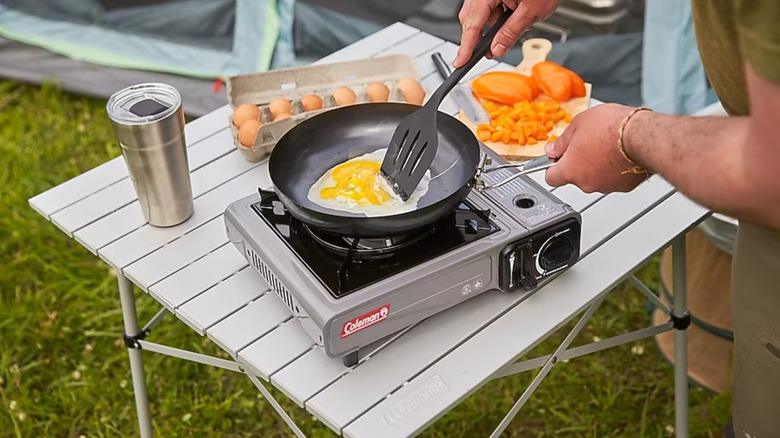 A camper cooking breakfast on a Coleman stove
