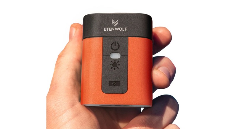 Person holding a compact orange etenwolf air pump