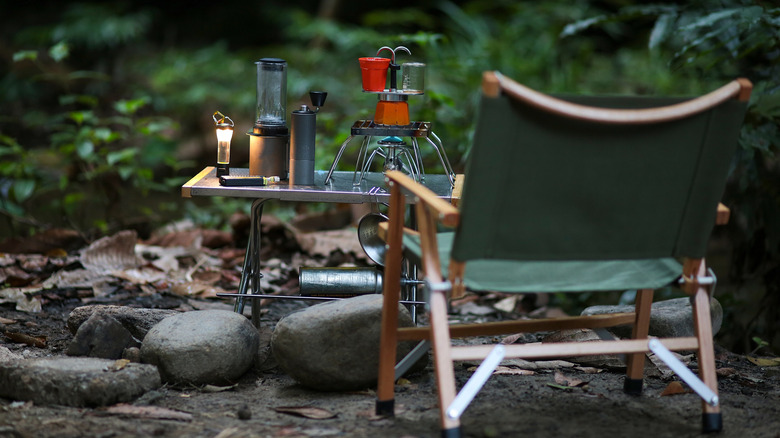 A camping chair alongside cooking camping gear on a campsite