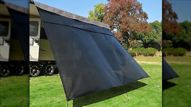 An awning shade installed outside an RV in an open garden.