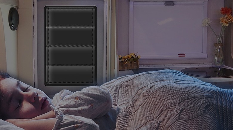 A girl sleeping inside an RV with windows and doors covered with a shade.