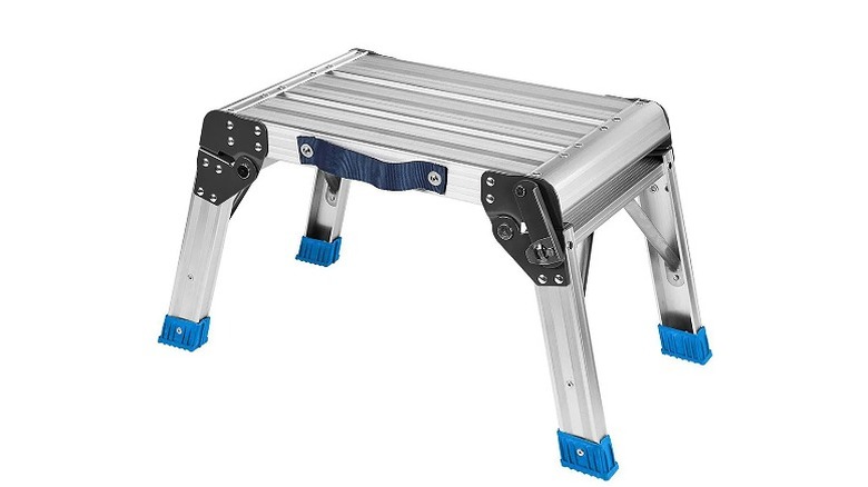 A silver, four-legged step stool against a white background.