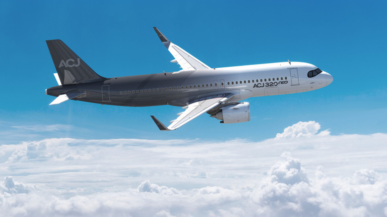 A gray and white Airbus ACJ320 Neo business or private jet banking at an angle while flying during the daytime.