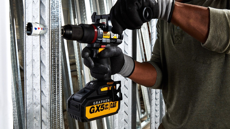 A worker using a Cat cordless hammer drill.