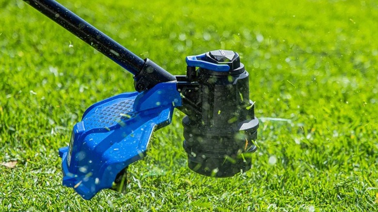 Close up of Kobalt string trimmer in use on a yard.
