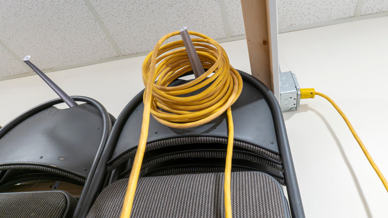 A carefully coiled yellow power cord stored on a peg.