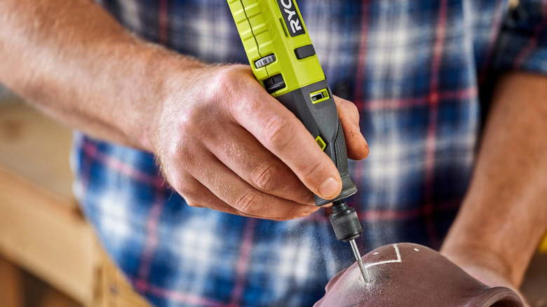 A person using a Ryobi rotary tool to make an incision.