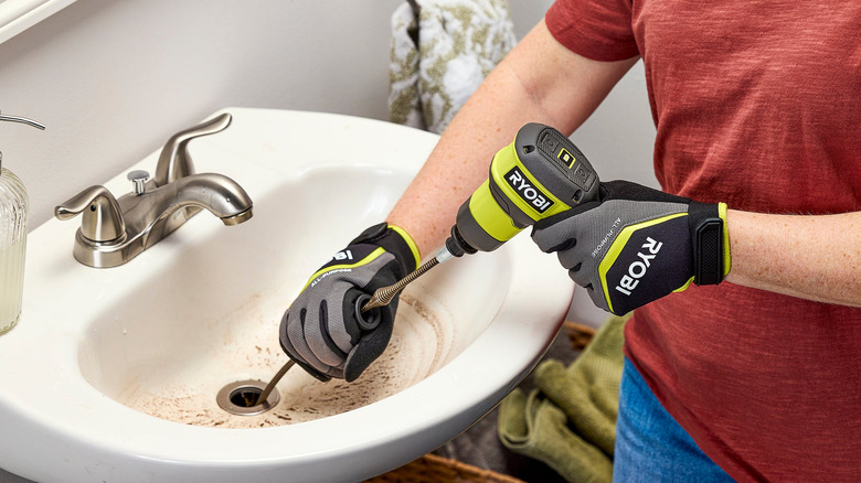Person using the Ryobi Cordless Drain Auger on bathroom sink.