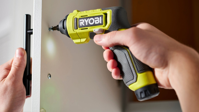 Hands using a small Ryobi power driver.