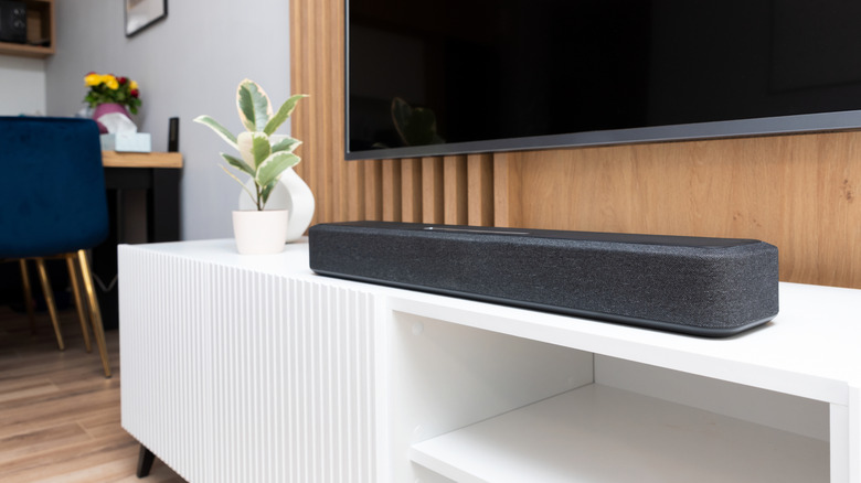 A soundbar placed under the television on a TV unit
