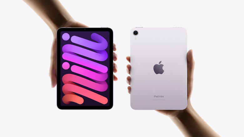 Two hands holding an Apple iPad Mini each on a white background