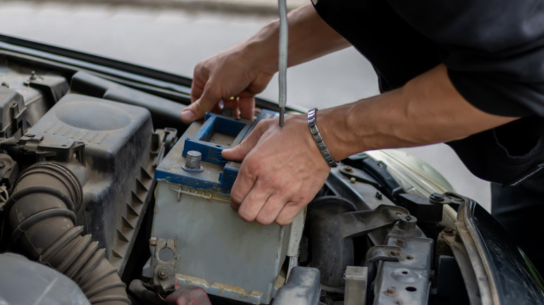 A person replacing a car battery.