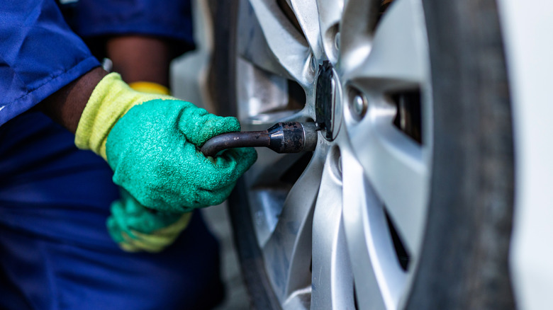 A person tightening the nuts on a tire.