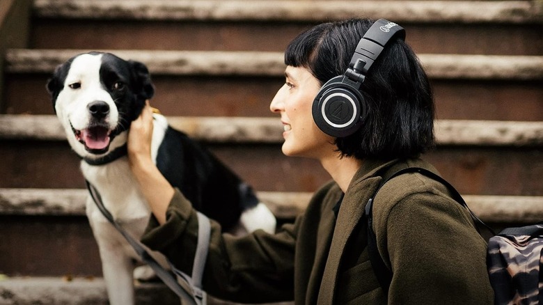 A person petting a dog while wearing Audio-Technica headphones