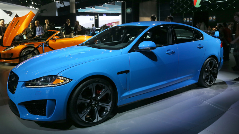 Blue Jaguar XFR Sedan parked at car show with orange convertible behind it