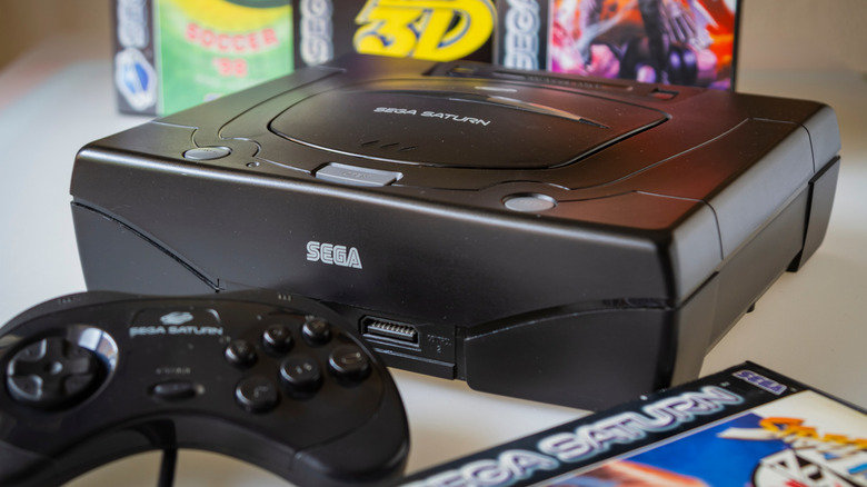 Close up of a Sega Saturn, its controller, and several games in their cases