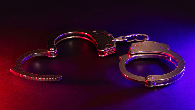 Close-up of handcuffs on a table with blue and red lighting