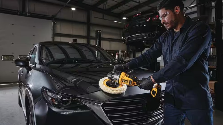 A worker using a DeWalt rotary polisher on a car.