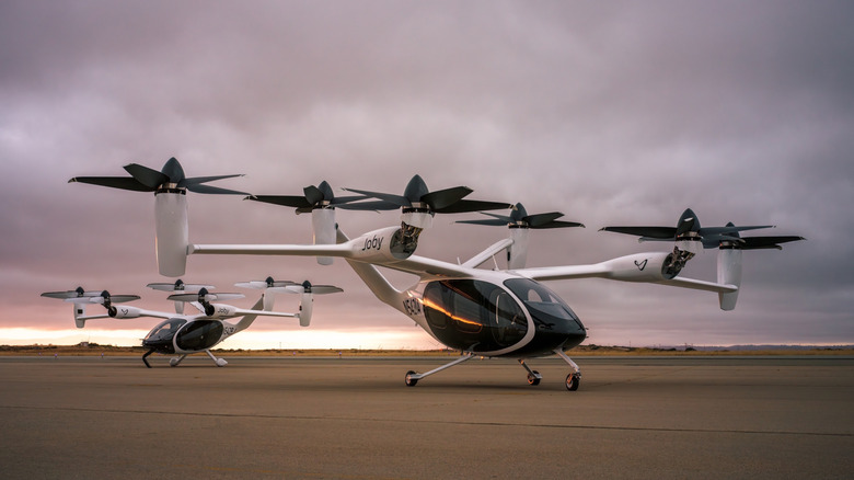 Two Joby air taxis on a runway at sunset.