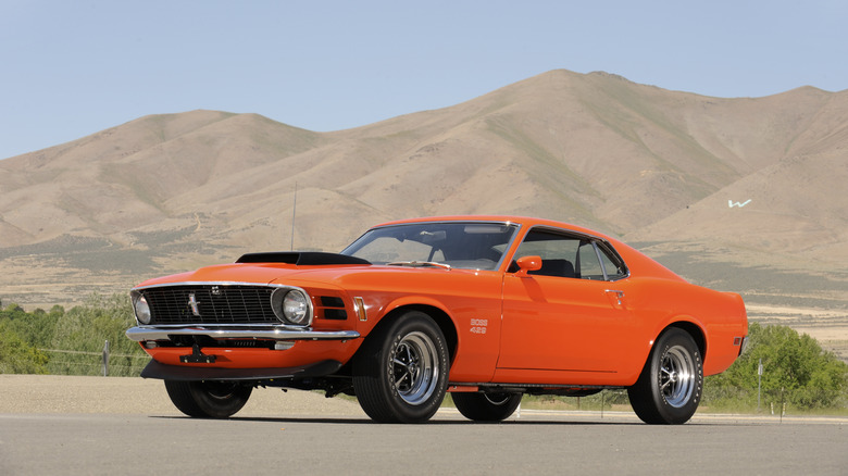 1969 Ford Mustang Boss 429 with desert background, front-left 3/4 view, orange exterior