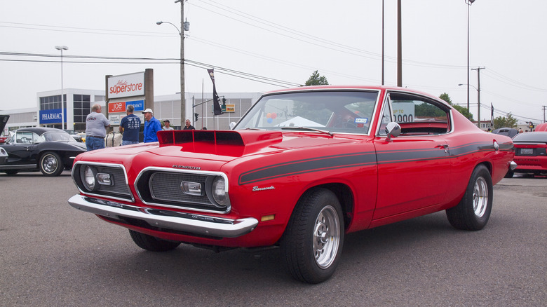 1969 Plymouth Barracuda with hood scoop at car show, front-left 3/4 view, drag tire setup, red exterior