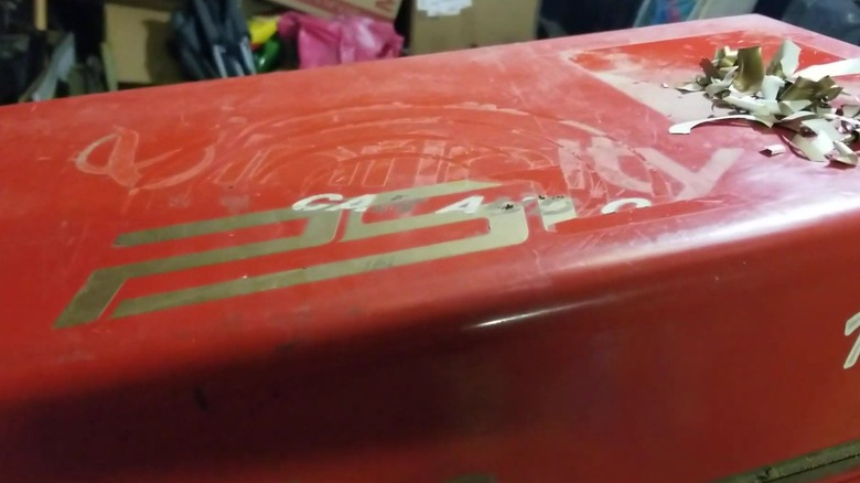 A metal toolbox covered in sticker residue.