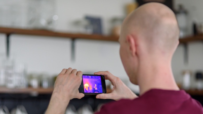 a person checking the space around a home with a thermal camera